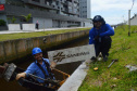 Empregados da Sanepar instalam ecobarreira em canal de Matinhos para conter lixo que iria ao mar 