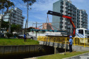 Empregados da Sanepar instalam ecobarreira em canal de Matinhos para conter lixo que iria ao mar 