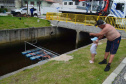 Empregados da Sanepar instalam ecobarreira em canal de Matinhos para conter lixo que iria ao mar 