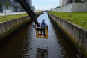 Empregados da Sanepar instalam ecobarreira em canal de Matinhos para conter lixo que iria ao mar 