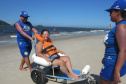 Com dificuldades extremas de caminhar, Débora Leia dos Santos tem tomado pelo menos dois banhos de mar por dia graças às cadeiras anfíbias disponibilizadas no Balneário Caieiras, no município de Guaratuba. Foto: Sanepar