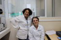 Estudantes paranaenses de graduação e pós-graduação contam com o apoio do Instituto de Tecnologia do Paraná (Tecpar) para o desenvolvimento de pesquisas acadêmicas que necessitam de equipamentos e laboratórios especializados. Na foto,  aluna de doutorado em Física da Universidade Federal do Paraná (UFPR), Deize Grodniski (sentada) e a colaboradora do Tecpar Luciana Barreto Adad, mestre em Engenharia e Ciência dos Materiais (em pé).  Foto: Divulgação/Tecpar