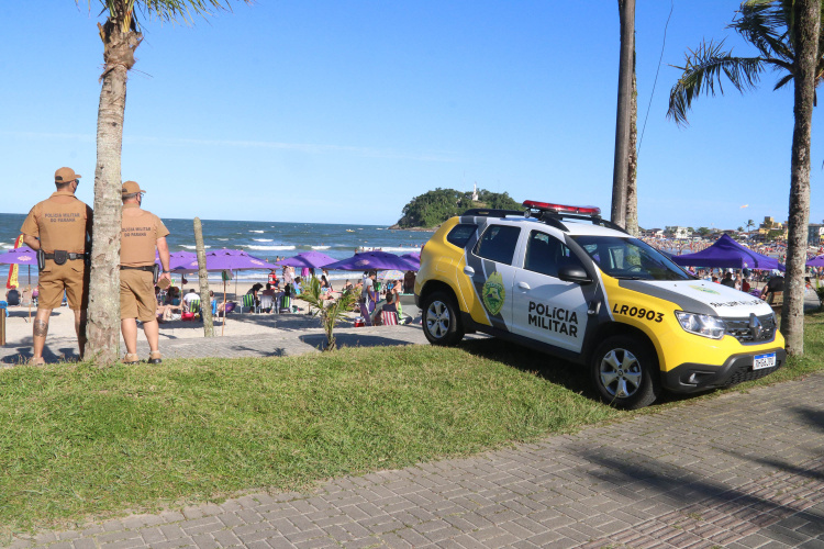 policiais militares observam a praia cheia de gente