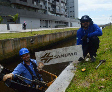 Empregados da Sanepar instalam ecobarreira em canal de Matinhos para conter lixo que iria ao mar 