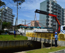 Empregados da Sanepar instalam ecobarreira em canal de Matinhos para conter lixo que iria ao mar 