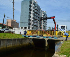 Empregados da Sanepar instalam ecobarreira em canal de Matinhos para conter lixo que iria ao mar 