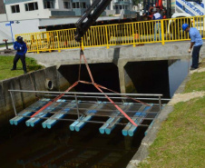 Empregados da Sanepar instalam ecobarreira em canal de Matinhos para conter lixo que iria ao mar 