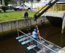 Empregados da Sanepar instalam ecobarreira em canal de Matinhos para conter lixo que iria ao mar 
