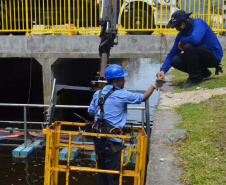 Empregados da Sanepar instalam ecobarreira em canal de Matinhos para conter lixo que iria ao mar 