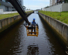 Empregados da Sanepar instalam ecobarreira em canal de Matinhos para conter lixo que iria ao mar 