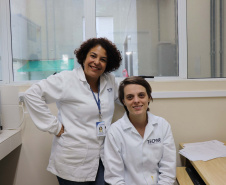 Estudantes paranaenses de graduação e pós-graduação contam com o apoio do Instituto de Tecnologia do Paraná (Tecpar) para o desenvolvimento de pesquisas acadêmicas que necessitam de equipamentos e laboratórios especializados. Na foto,  aluna de doutorado em Física da Universidade Federal do Paraná (UFPR), Deize Grodniski (sentada) e a colaboradora do Tecpar Luciana Barreto Adad, mestre em Engenharia e Ciência dos Materiais (em pé).  Foto: Divulgação/Tecpar