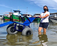 A cadeira anfíbia, com pneus adaptados, facilitou a vida de dona Francisca Alves de Lima, 75 anos, ao visitar a Ilha do Mel, no Litoral do Paraná. Com má circulação nas pernas, ela foi a primeira usuária do benefício, disponibilizado pelo Instituto Água e Terra (IAT) desde o dia 7 de janeiro deste ano.  -  Foto: Divulgação SEDEST/IAT