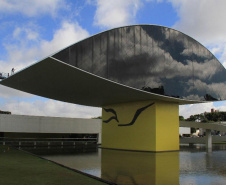 Obra do Paranacidade, o MON foi erguido em seis meses de trabalho ininterrupto. Maior Museu da América Latina, o Museu Oscar Niemeyer é um exemplo de arquitetura aliada à arte. Mais conhecido como museu do olho, por causa da sua torre, uma grande estrutura oval em vidro, o MON foi inaugurado em 2002 e sua construção chegou a ter 700 operários trabalhando em três turnos, 24 horas por dia.  -  Foto: Divulgação Paranacidade