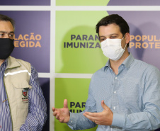 O  Secretário de Estado da Saúde, Beto Preto e o vice-prefeito Eduardo Pimentel recebem o primeiro lote de  32.760 doses de vacinas contra a Covid-19 da  Pfizer   no Centro de Medicamentos do Paraná (Cemepar), em Curitiba, na noite desta segunda-feira (3).  Foto: Geraldo Bubniak/AEN
