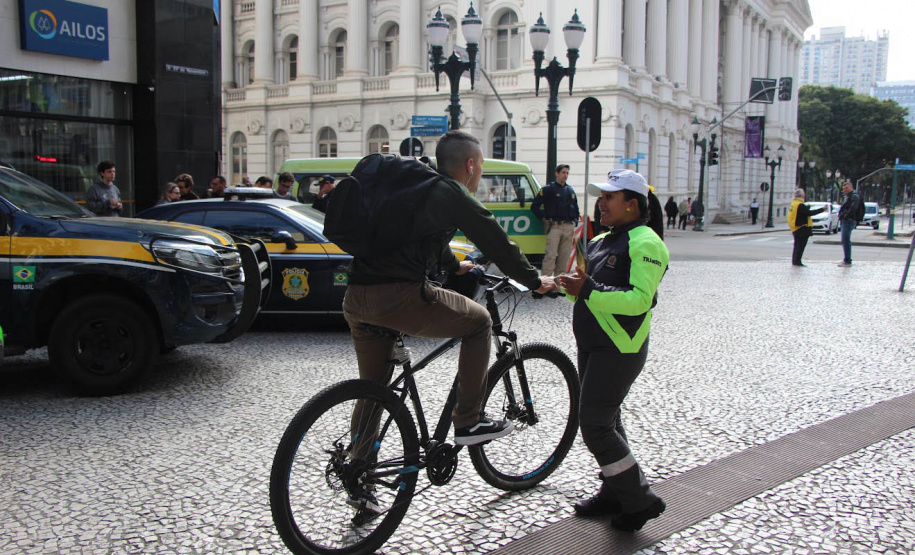 Ciclistas e pedestres da XV de Novembro, em Curitiba, recebem materiais educativos do trânsito