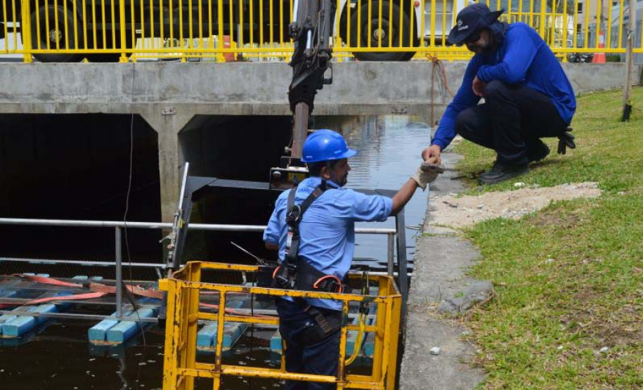 Empregados da Sanepar instalam ecobarreira em canal de Matinhos para conter lixo que iria ao mar