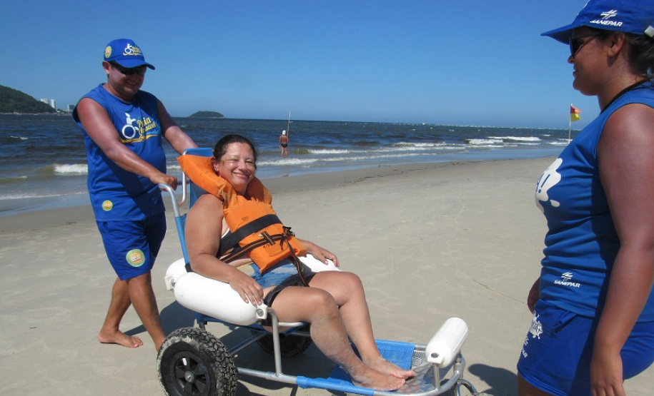 Com dificuldades extremas de caminhar, Débora Leia dos Santos tem tomado pelo menos dois banhos de mar por dia graças às cadeiras anfíbias disponibilizadas no Balneário Caieiras, no município de Guaratuba. Foto: Sanepar