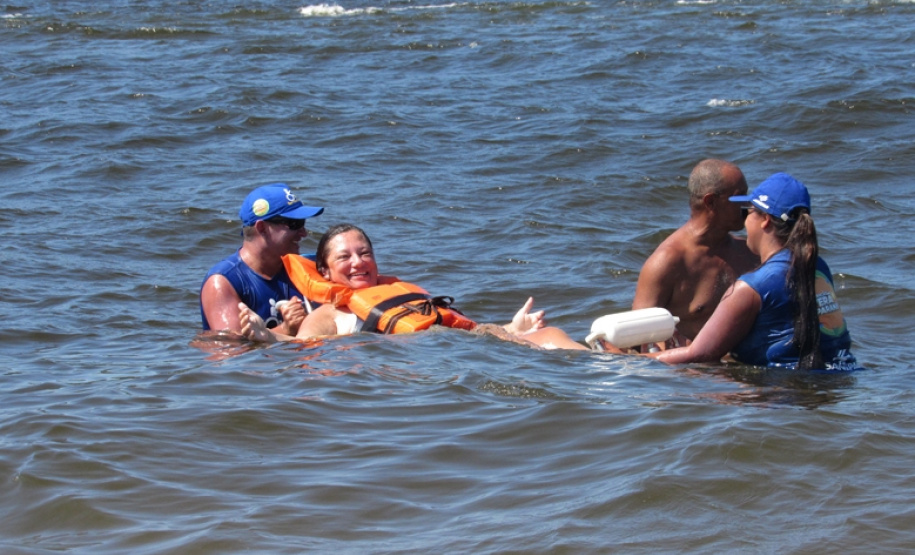 Com dificuldades extremas de caminhar, Débora Leia dos Santos tem tomado pelo menos dois banhos de mar por dia graças às cadeiras anfíbias disponibilizadas no Balneário Caieiras, no município de Guaratuba. Foto: Sanepar