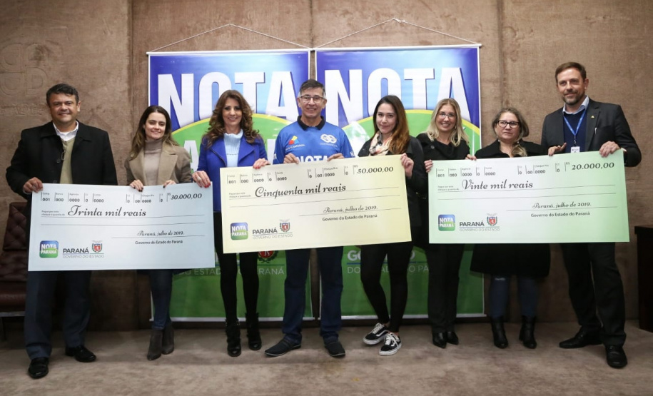 Todas de Curitiba e todas mulheres. São da Capital as três felizes ganhadoras dos prêmios do Nota Paraná deste mês de julho. Os cheques, de R$ 50 mil, R$ 30 mil e R$ 20 mil, foram entregues nesta quinta-feira (18) às três moradoras de Curitiba dos bairros Mossunguê, Hugo Lange e Campo Comprido. Foto: Gilson Abreu/ANPr