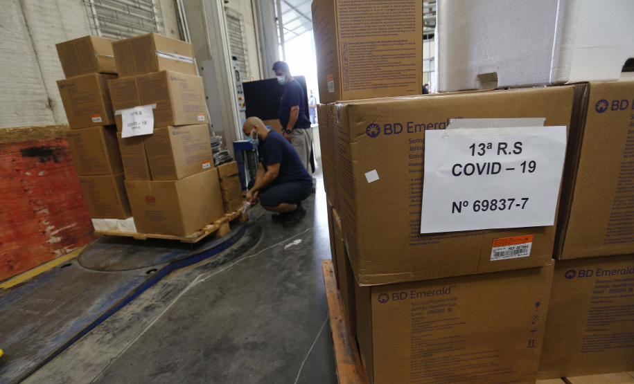 A Secretaria da Saúde do Paraná vai dar início neste sábado (16) à distribuição da primeira remessa de insumos destinados à vacinação da Covid-19 no Estado. Quatro caminhões vão sair pela manhã da central de abastecimento e suprimentos da secretaria, no Jardim Botânico, em Curitiba, carregados com 2,2 milhões de itens que serão entregues a 20 Regionais de Saúde do Estado. 
 Foto:Jonathan Campos/AEN